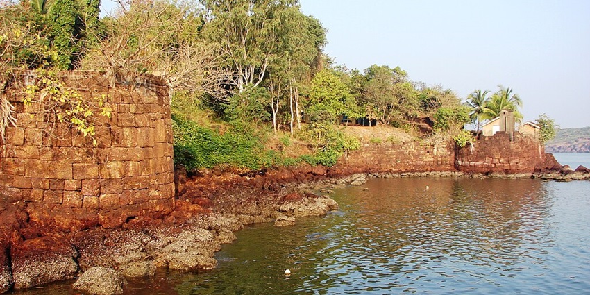An Image of the Devgad fort, a sea fort in India, with an old stone wall and greenery