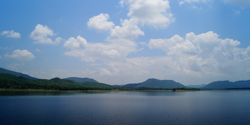 Dimna Lake with a large water body, green and sandy shores and distant mountains