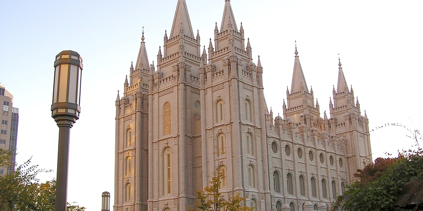 Green trees and adjacent buildings surround the Salt Lake Temple Square in Utah