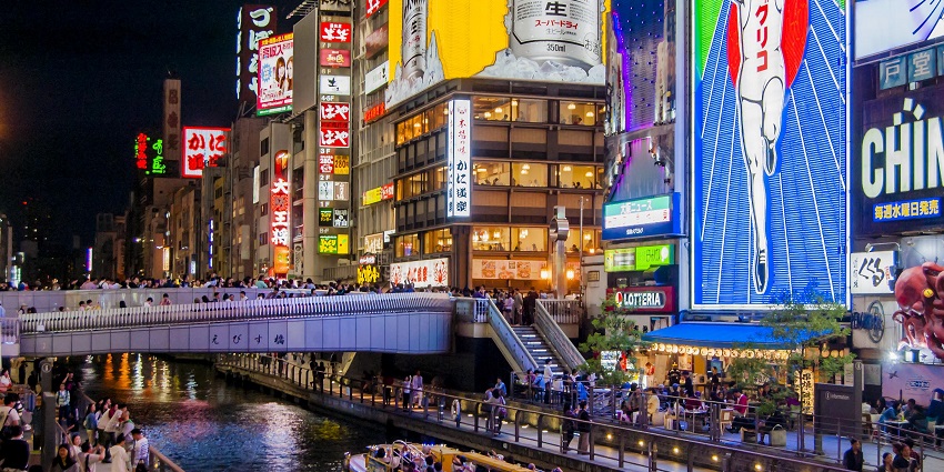 Japan nightlife in the Osaka district with neon lights, street food, and entertainment.