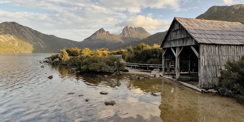 An image of Dove Lakes in Australia, with a boat shed and Cradle Mountain in the background