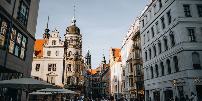An Image of the old town of Dresden with people walking in the streets and tall buildings around.