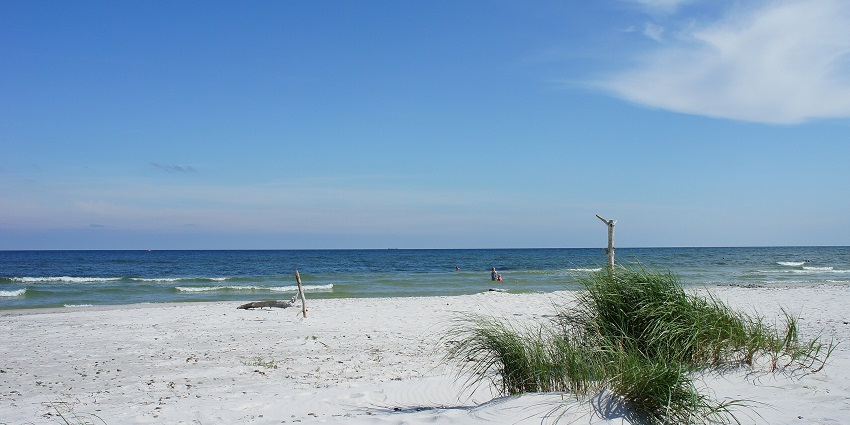 An image of Dueodde Beach with white sandy shores and clear blue waters.
