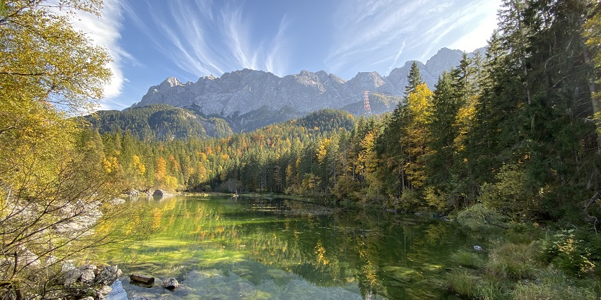 Image of Eibsee Lake in Germany that is surrounded by rocky shores and tall green trees