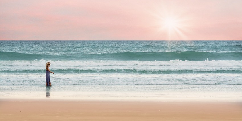 View of El Saler Beach, a girl peacefully walking by the waves at Valencia beaches.