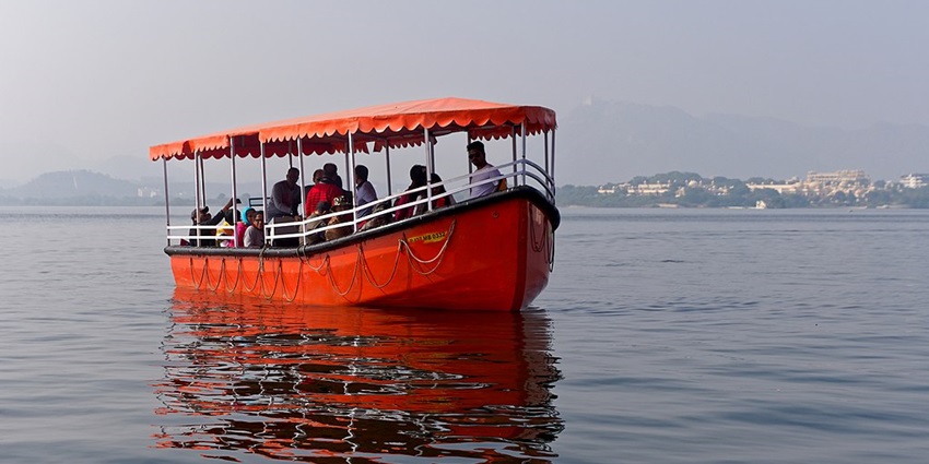 A tourist boat at Lake Pichola with mesmerising views of Udaipur city and mountains.