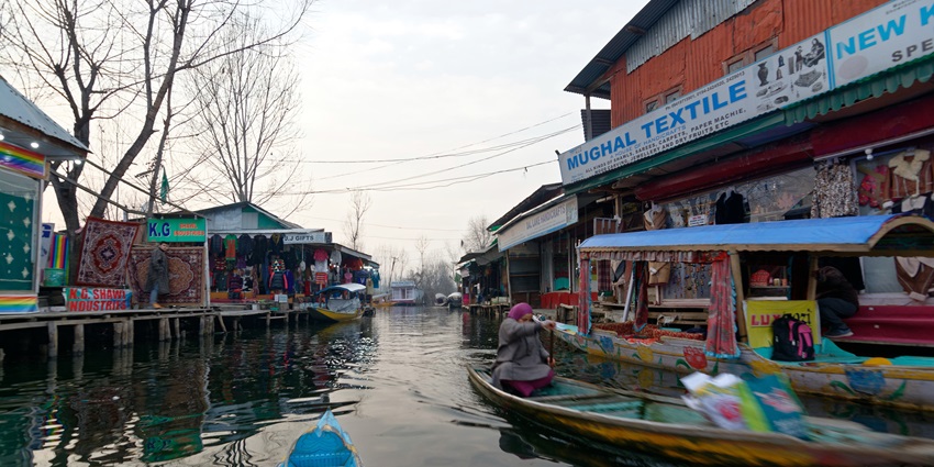 Colourful scene of boats with goods in the floating market surrounded by shops and hills
