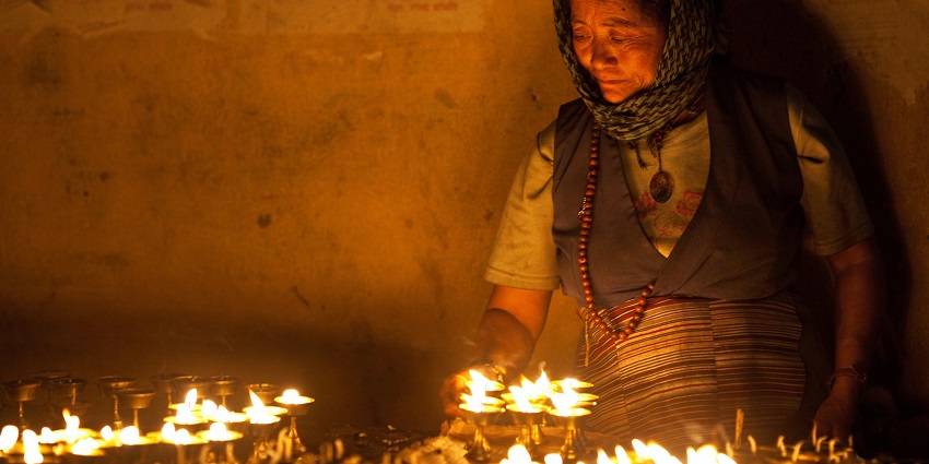 Tibetan woman lights incense butter candles in honor of Losar holiday