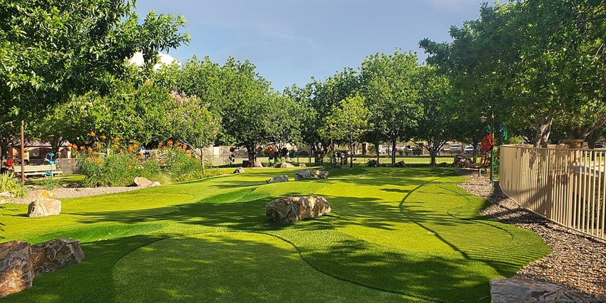 A mini golf course on a sunny day covered with velvet-green grass and different trees