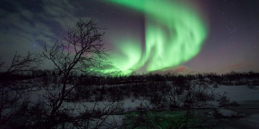 An image of the northern lights over Tromsø’s snowy landscapes, a unique thing to see in Norway.