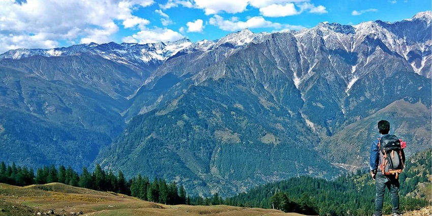 A man with his backpack stops and takes in scenic views en route to the Bhrigu Lake Trek.