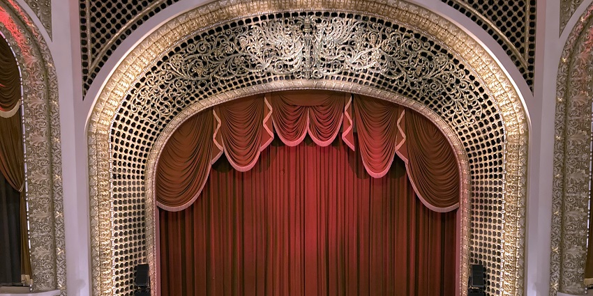 Image of the interior of a famous theatre with colourful lights and red curtain on stage