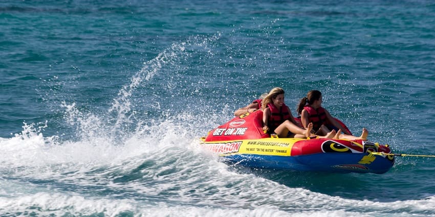 Two women wearing safety gear enjoy water sports in the Maldives.