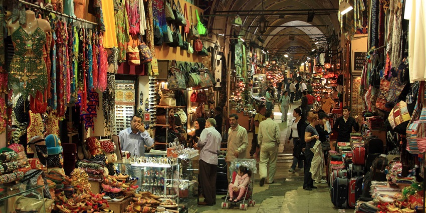A bustling market with shoppers exploring vibrant textiles and colourful handcrafted goods