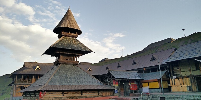 Prashar Temple beside the lake in summer with a unique grey architecture and multiple sign boards in front.