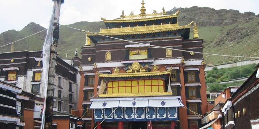 A towering Maitreya Buddha statue adorned in golden hues, set against a mountainous backdrop