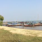 Chilika Lake in Odisha with multiple different coloured boats parked on the sandy shore