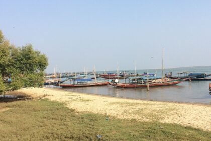 Chilika Lake in Odisha with multiple different coloured boats parked on the sandy shore