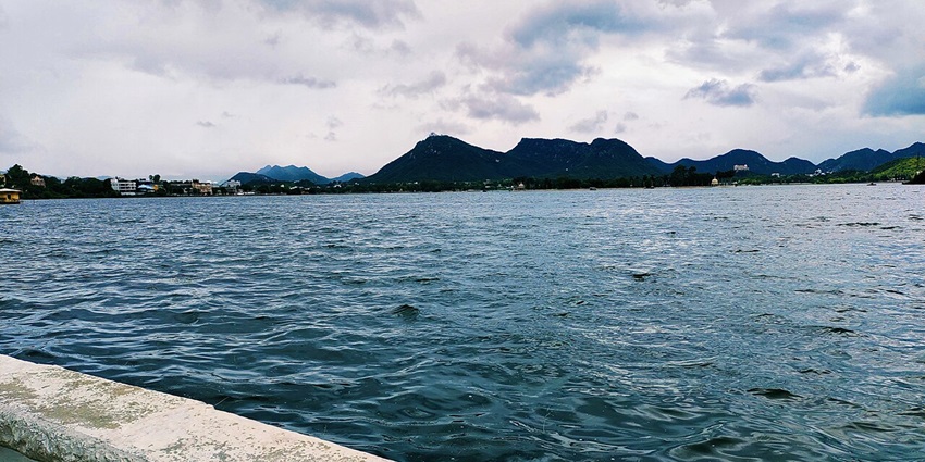 An image of Fateh Sagar Lake in Rajasthan with surrounding hills, and a scenic landscape