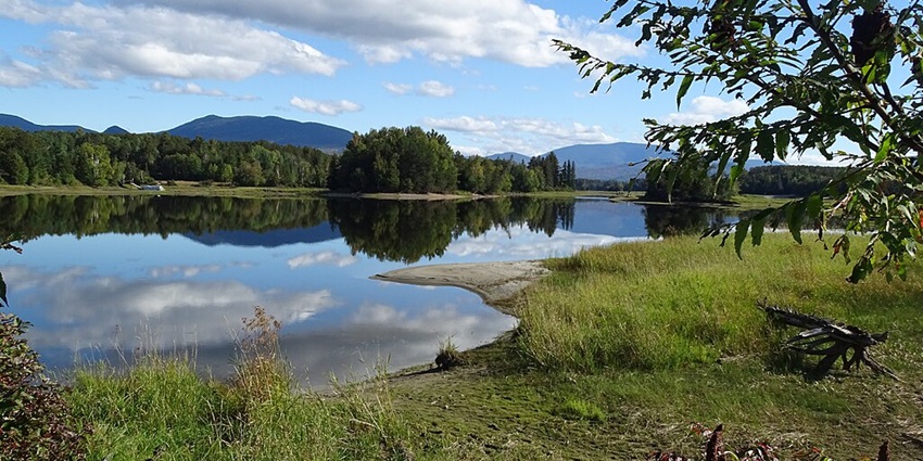 The Flagstaff Lake reflects fluffy clouds with the Bigelow Mountains in the background.