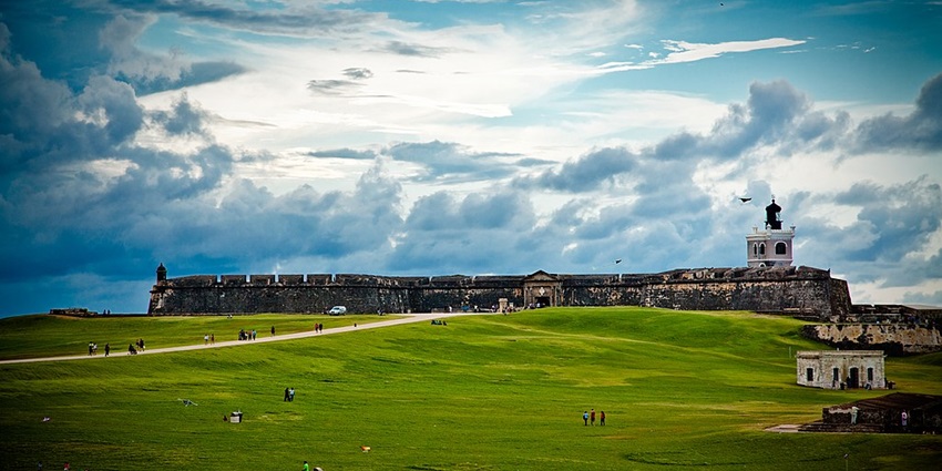 El Morro fortress in San Juan, Puerto Rico, with a green field and dramatic cloudy sky