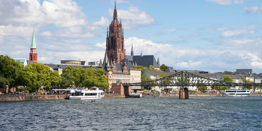 An image of Frankfurt, Germany, featuring the Main River, Eiserner Steg bridge, and Frankfurt Cathedral.