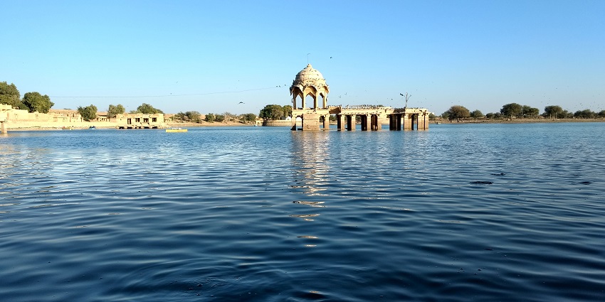 Gadisar Lake with a large water body and a traditional architectural structure in the middle.