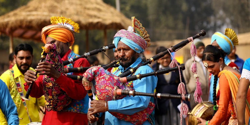 Group wearing colorful traditional attire standing outdoors, smiling together