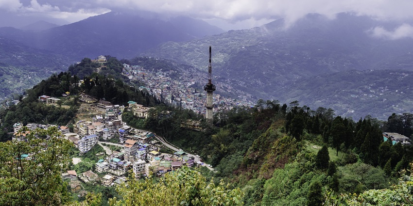 Hill town view of Gangtok with colorful buildings and the Himalayas in the distance.