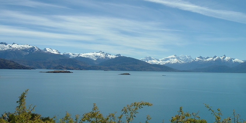 An image of the lakes in South America with lush green hills in the background.