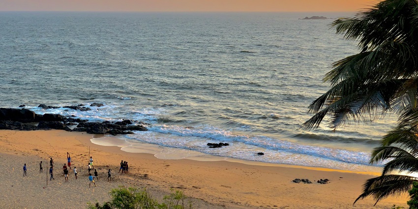 An image of a scenic beach of Goa with a sandbar, surrounded by water and dense forest in the background