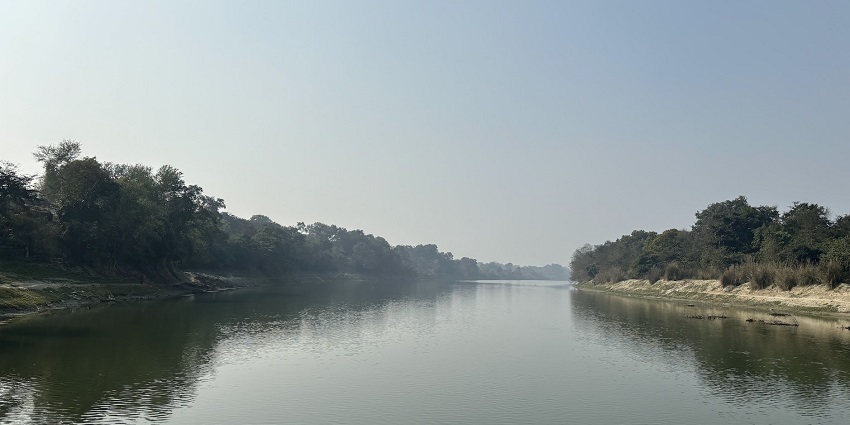 An image of Gomti River in summer with a rocky riverbed, low water levels, and a hazy sky.