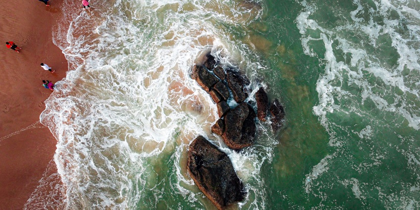 An image showing Gopalpur Sea Beach with waves touching the sandy shore under a clear sky.