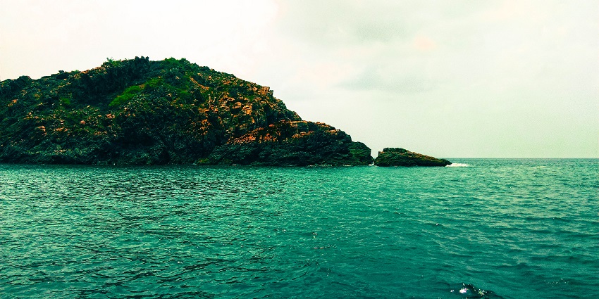 An image of a rocky island surrounded by the ocean water in Goa for snorkelling in India
