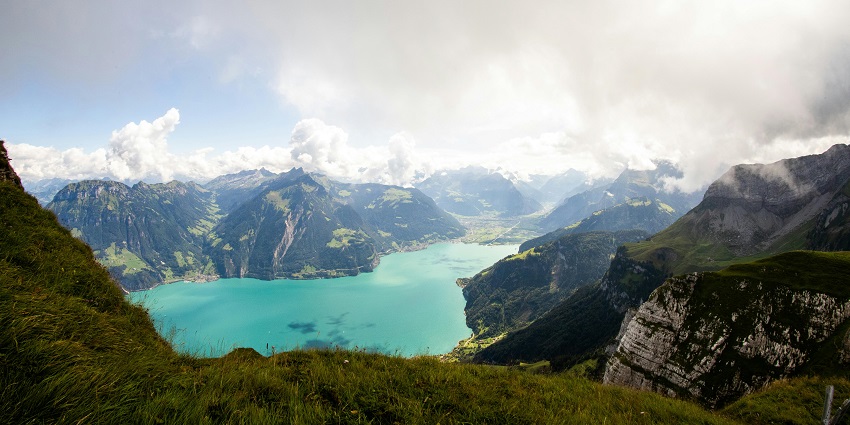 Lake from the top with a bright cyan water body surrounded by big green mountains