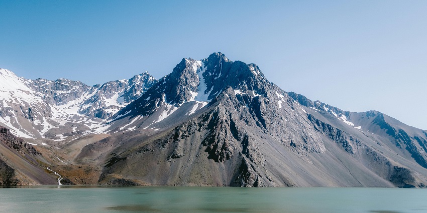 Landscape of a lake in North Sikkim with greyish mountains in the background with snow-covered peaks.