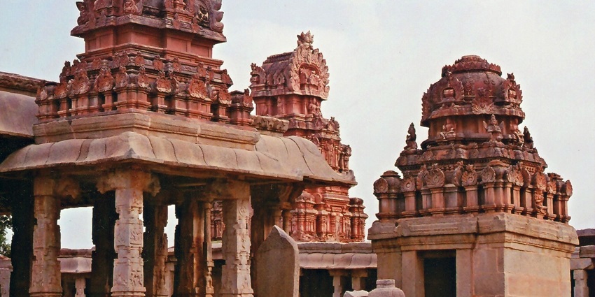 Ancient stone ruins and boulders dot the dramatic landscape of Hampi at sunset.