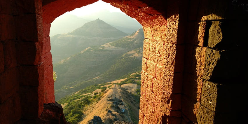 An image of Harihar Fort showcases its impressive steep steps and scenic views from the top.