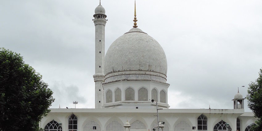 Hazratbal shrine with white architecture, windows on the shrine and a green lawn area