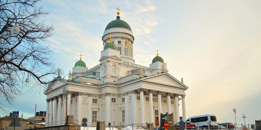 An image of Helsinki Cathedral with its striking white exterior, green domes, and steps.