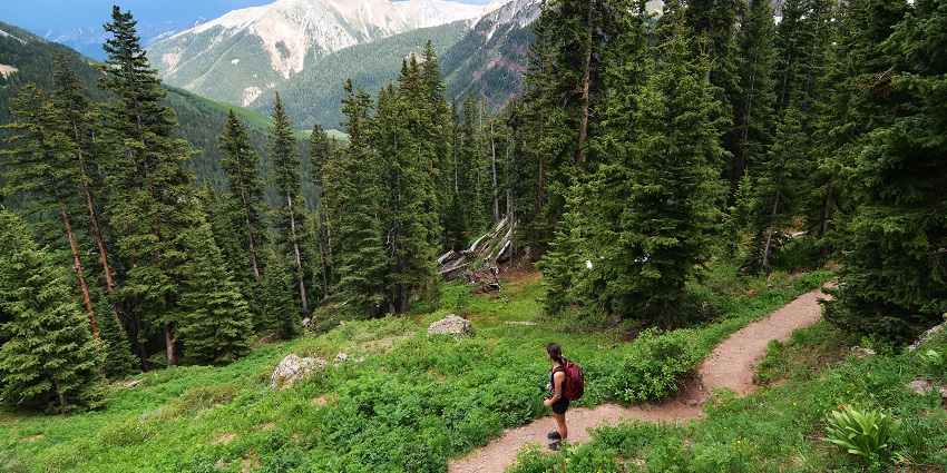 A man stands at a hiking trail and looks at the surrounding mountain, one of the best things to do at Lake Como.