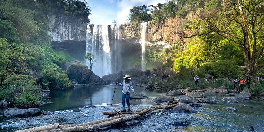 A thrilling trek leading to a majestic waterfall surrounded by towering cliffs and alpine scenery