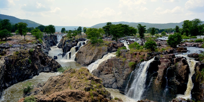 A magnificent view of the Hogenakkal Falls, with water flowing through rocky formations.