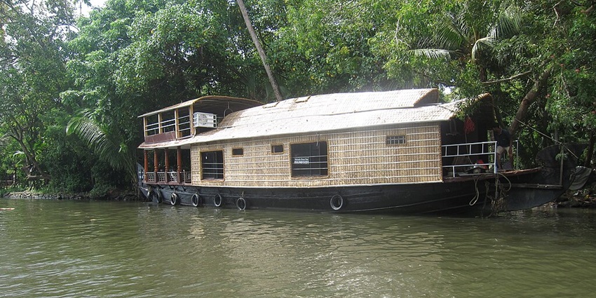 An image of a luxurious houseboat sailing through the serene waters of Vembanad Lake.