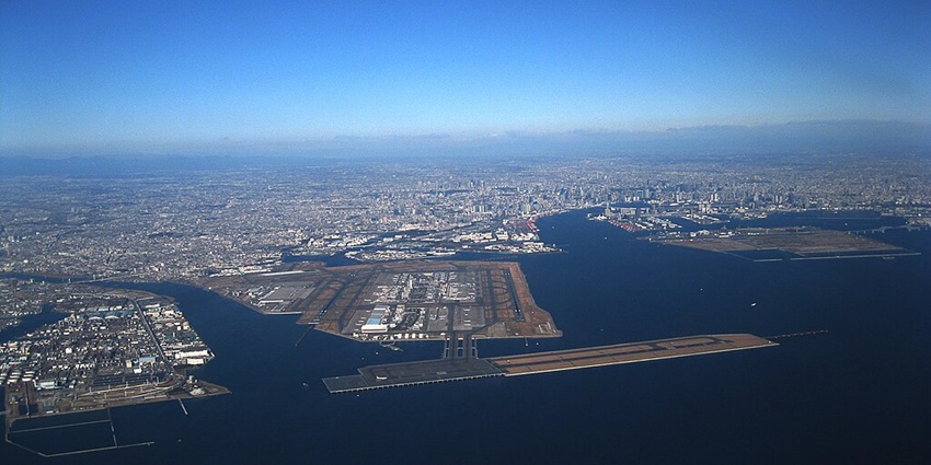 Aerial view of Tokyo Haneda Airport, showcasing its modern terminals and runways.