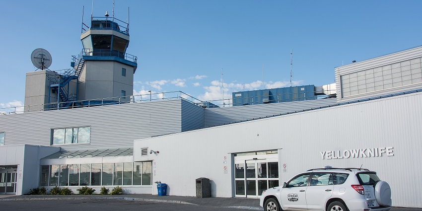 White coloured car parked outside the Yellowknife airport terminal.