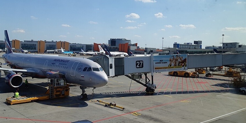 Airport in Russia with a spacious terminal, large windows, and passengers walking through.