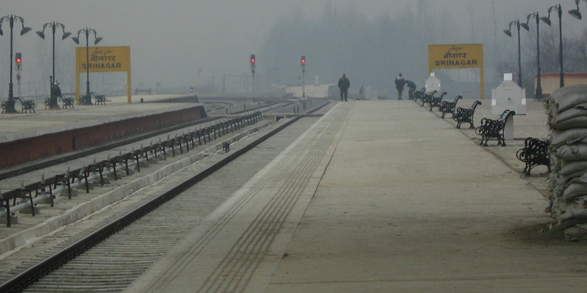 Srinagar railway station with two train platforms, two signboards, benches and people