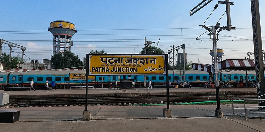 Patna Junction railway station with a train on the platform and a power line structure.