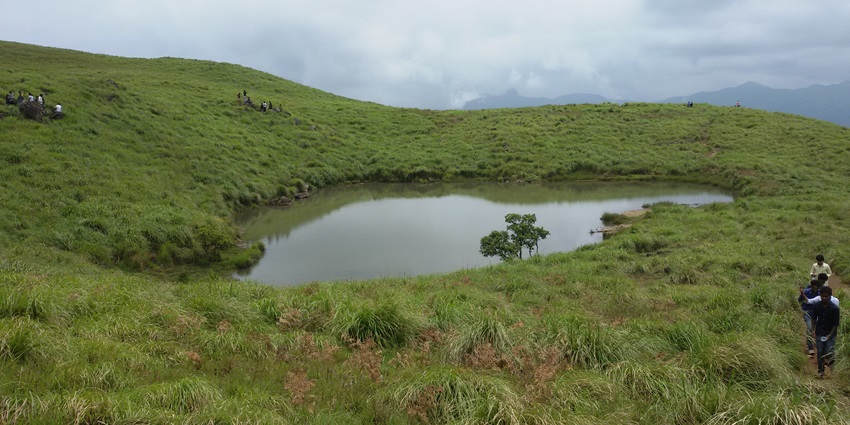 Trekkers hiking through and enjoying lush trails towards the Heart Shaped Lake in Kerala.